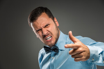 Portrait angry upset young man in blue shirt, butterfly tie