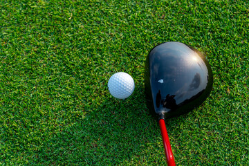 Close up golf club and golf ball ,professional golfer teeing golf ball to hole at golf course to win in game ,green grass and sunlight rays background