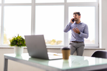 Business man working on computer at office calling on phone.
