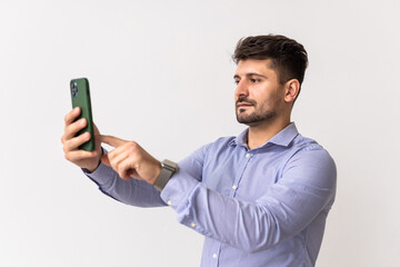 Profile view of serious young casual man holding cellphone taking photo isolated over white studio background.