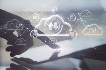 Close up of hand pointing at tablet on desktop with abstract glowing cloud computing hologram with download/upload arrows on blurry background. Database, technology and future concept. 