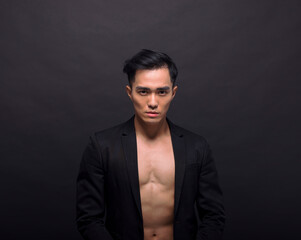 Strong, fit and handsome asian young  man over black background