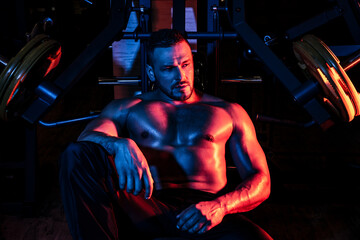 Tired sporty man resting after training. Man with bottle of water or protein. Athletic guy at gym.