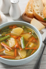 Bowl of tasty turnip soup and spoon on white wooden table