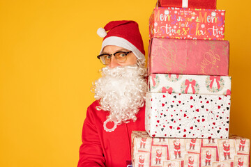 Santa Claus brought gifts for Christmas. Modern young santa on yellow background