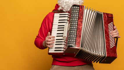 Modern Santa Claus play accordion emotionally isolated on yellow background