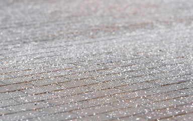 Rock salt (sodium chloride) spread on paving slabs for de-icing, prevent slipping. Paving slabs sprinkled with rock salt, deicing chemicals on pavement. Shallow depth of field, selective focus