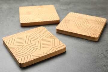 Stylish wooden cup coasters on grey table
