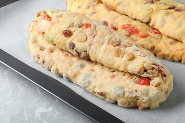 Baking tray with raw homemade Stollens on grey marble table, closeup. Traditional German Christmas bread