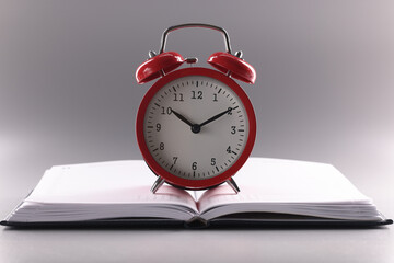 Red retro clock stand on top of open notebook or book