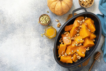 Healthy dessert or vegan lunch. Baked pumpkin. Delicious baked sweet pumpkin with nuts, pumpkin seeds and honey over gray stone background. Top view flat lay. Copy space.