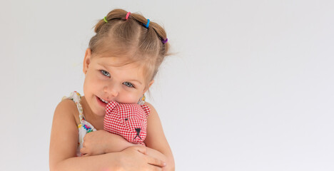 Portrait of beautiful caucasian little girl of 3 years hugging red teddy bear on white background with copy space
