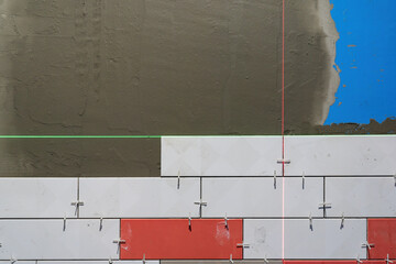 Part of the wall in the room is covered with white and red tiles. There is a surface covered with...