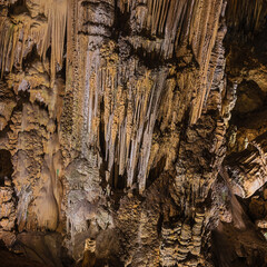 Stalactites with fine colorful and delicate structures in the Nerja cave. Selective focus on the nearby column.