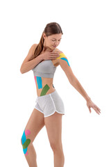 Woman shows kinesio tapes on her shoulder. Bright medical tape on the abdomen, shoulder and leg - obrazy, fototapety, plakaty