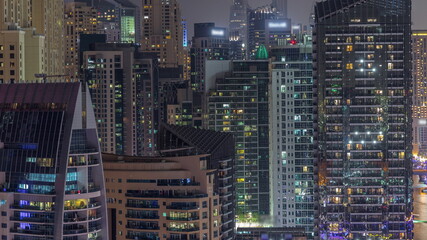 Fototapeta na wymiar Modern skyscrapers in Dubai Marina, close up view to many illuminated windows aerial night timelapse.