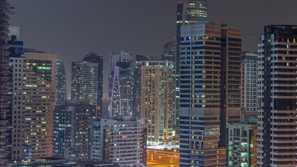 Fototapeta na wymiar Modern skyscrapers in Dubai Marina, close up view to many illuminated windows aerial night timelapse.