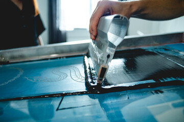 Cropped shot of craftsman applying plastisol ink on screen printing machine 