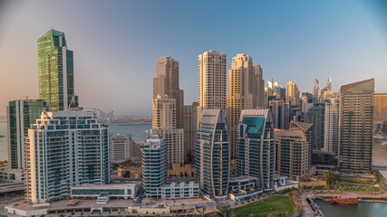 Dubai Marina with several boat and yachts parked in harbor and skyscrapers around canal aerial timelapse.