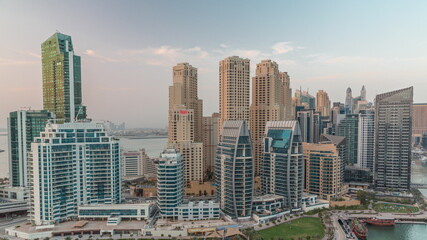 Fototapeta na wymiar Dubai Marina with several boat and yachts parked in harbor and skyscrapers around canal aerial day to night timelapse.