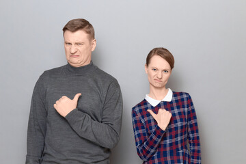 Portrait of disgruntled man and woman  pointing at each other