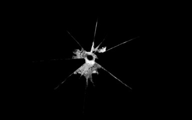 a crack on a broken glass mirror on a black background lines fragments bullet hole