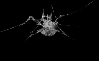 a crack on a broken glass mirror on a black background lines fragments bullet hole
