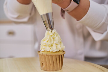 Pastry bag with white cream. Making homemade cupcakes with a pastry bag. process of decorating...