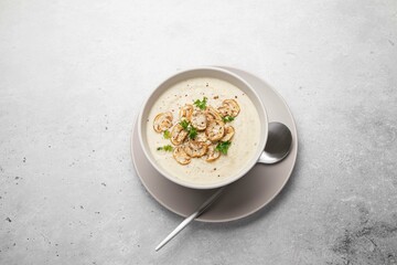 Bowl with mushroom champignon cream soup on grey table. Top view, copy space. Selective focus.