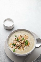 Bowl with mushroom champignon cream soup and salt on grey table. Top view, copy space. Selective focus.