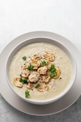 Bowl with mushroom champignon cream soup on grey table. Top view, copy space. Selective focus.