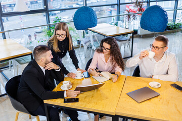 Meeting of business people, discussing new business ideas, using diagrams, sitting together. Modern office background. Meeting of business partners at a business development conference