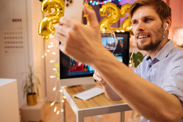 Christmas and New Year eve party 2022. Virtual work meeting in video call. Holiday office xmas at home. Decorate foil balloons of 2022 and Christmas lights. smiling man with waving hand. Selfie video