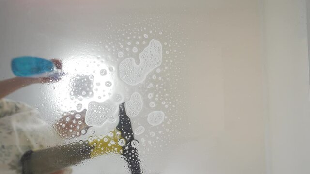 Cleaning the living room, handheld window vacuum cleaner cleaning table glass surface sucking up detergent foam close-up. High quality 4k footage