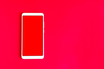 The concept of online shopping. A white phone with a red screen, on a bright red background copy space.