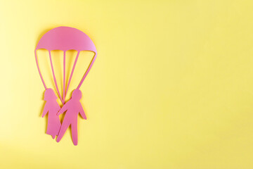 Abstract cardboard family of two people and a rescue parachute. Minimalistic picture of protecting...