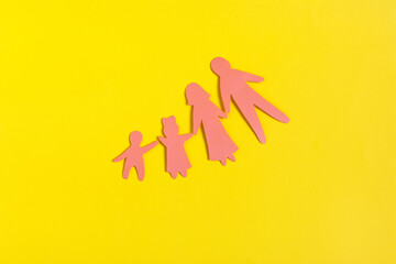 Abstract paper family consisting of two adults and two children on a yellow background close-up