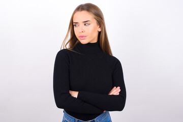 Displeased Young caucasian girl wearing black turtleneck over white background with bad attitude,...