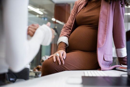 Midsection of female colleagues discussing in office