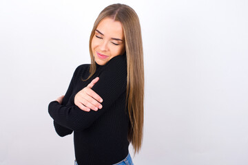 Young caucasian girl wearing black turtleneck over white background  Hugging oneself happy and positive, smiling confident. Self love and self care.