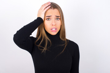 Portrait of confused Young caucasian girl wearing black turtleneck over white background holding hand on hair and frowning, panicking, losing memory. Worried and anxious can not remember anything.