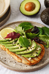 Toast with sliced avocado, fresh salad on plate