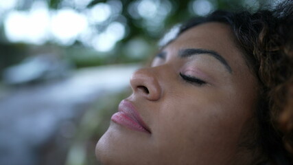 Brazilian person closing eyes taking a deep breath feeling free emotion fresh air