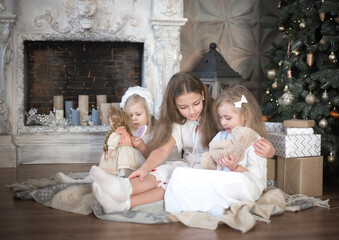 Obraz na płótnie Canvas Little girls play near the fireplace in the morning before Christmas. Retro style. Winter holidays, Christmas, New Year.