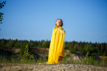 Beautiful blonde girl posing in a yellow dress in nature. Summer photo. Blue sky. Sunny day.
