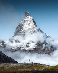 Hiker man walks alone through the incredible Swiss Alps with the Matterhorn in the background...