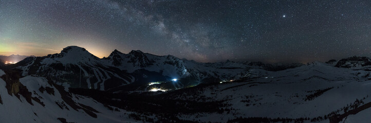 Wonderful starry sky milky way and majestic mountain range in Sunshine Village. Ski village at night. Winter landscape with village in mountains, Banff, Canada
