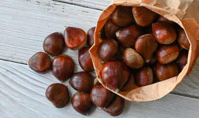 Chestnuts in a paper bag on a wooden background