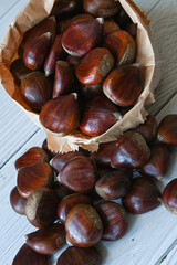 Chestnuts in a paper bag on a wooden background