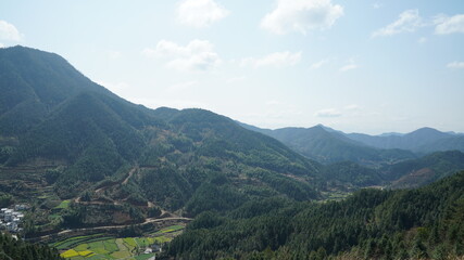 The beautiful mountains view with the green forest and flowers field in the countryside of the southern China 